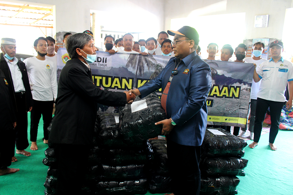 Ketua DPW LDII Jawa Timur KH. Moch. Amrodji Konawi menyerahkan bantuan berupa 1.100 pakaian dan masker kepada warga di Posko Pengungsian erupsi gunung Semeru.