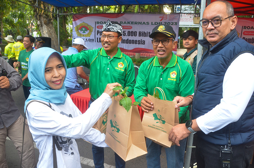 Sekretaris Dinas Lingkungan Hidup Kota Surabaya Achmad Eka Mardijanto (kanan) bersama Pengurus DPW LDII Jawa Timur membagikan bibit tanaman kepada warga. Dok: LINES.